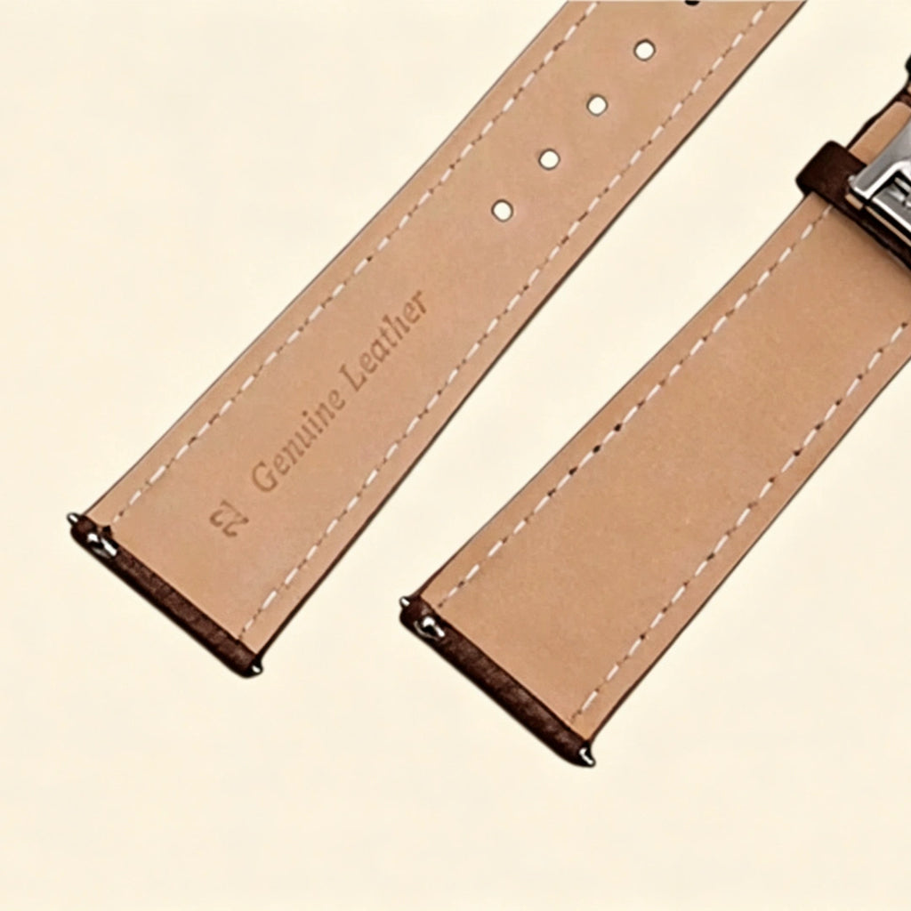 Baroque Archival Suite No. 10849 — silver engraved case with dark espresso brown leather strap and silver cross emblem stud, three-quarter product shot on cream background