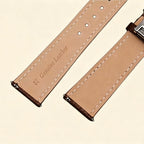 Baroque Archival Suite No. 10849 — silver engraved case with dark espresso brown leather strap and silver cross emblem stud, three-quarter product shot on cream background