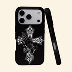 The Devotional Emblem case – angled top floating view showing praying hands over ornate silver gothic cross on matte black