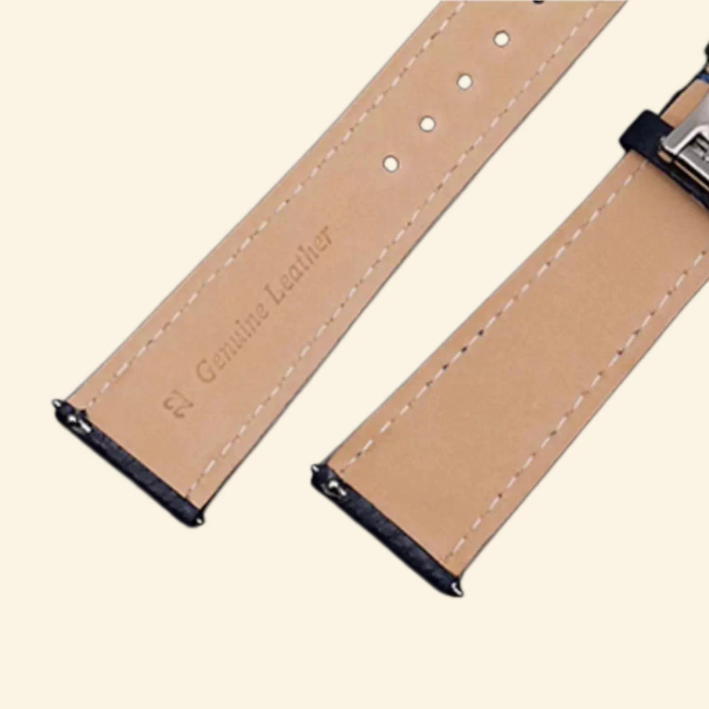 Baroque silver Apple Watch case with navy leather strap — front three-quarter wrist angle showing full scrollwork bezel and cross emblem, cream background