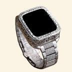Baroque silver engraved Apple Watch case with pavé crystal stainless steel bracelet — three-quarter front view showing full scrollwork bezel and crystal-set links, cream background