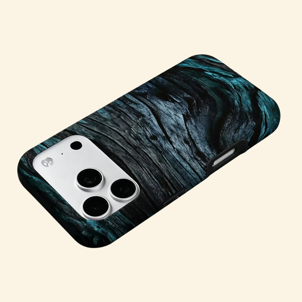The Ancient Sediment case – hand-held lifestyle shot showing full dark wood grain texture with deep teal and cobalt tonal depth