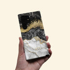Gold Vein Obsidian Marble Case — held in hand lifestyle shot